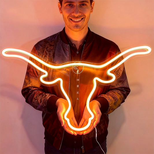 Man holding a neon sign of a bull's head against a plain background