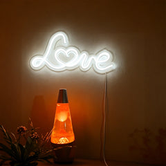 Neon sign spelling 'Love' above a lava lamp on a dark background