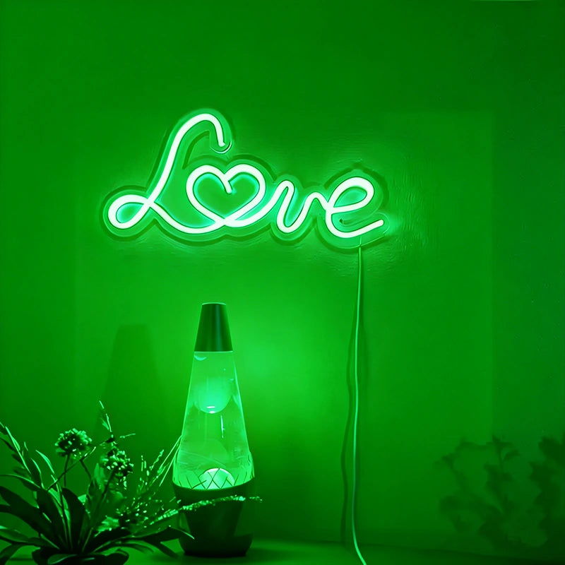 Neon sign with 'Love' on a green background, next to a lava lamp.