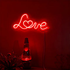 Neon sign with the word 'Love' on a dark red background, accompanied by a lava lamp.