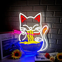 Neon light shaped like a maneki neko fortune cat eating noodles against a brick wall.