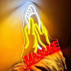 Neon sign shaped like hands with a foot and the word 'MASSAGE' on a textured surface.