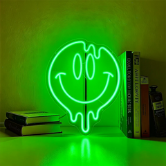 Neon light shaped like a smiley face on a green background with books below.