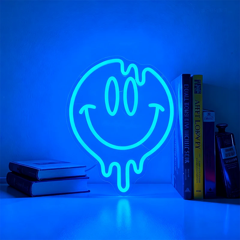 Neon light shaped like a blue smiley face on a shelf with books and a bottle.