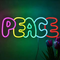 Neon sign spelling 'PEACE' with colorful lights on a dark background