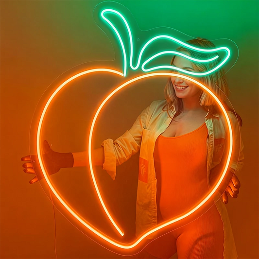 Woman holding a neon light shaped like a peach design against a gradient background.