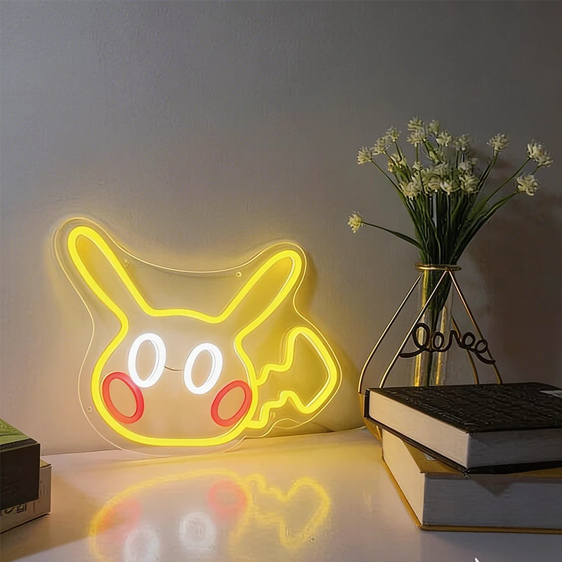 Neon sign shaped like a cartoon character pikachu on a table with books and a vase.