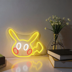 Neon sign shaped like a cartoon character pikachu on a table with books and a vase.