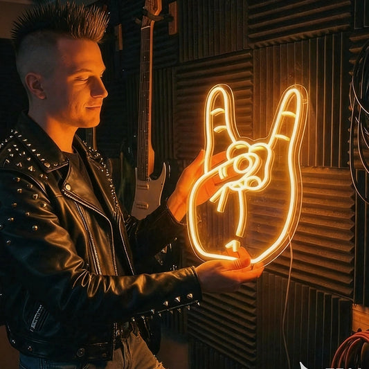 A man in a black studded leather jacket holds a glowing orange neon sign shaped like a hand with a rose, set against a dark acoustic foam wall with guitars hanging in the background.
