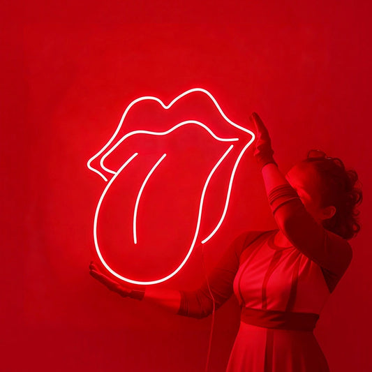 A person holding a glowing red rolling stone logo neon sign against a solid dark wall.