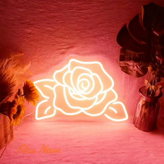 Neon rose warm white light on a pink background with decorative plants.