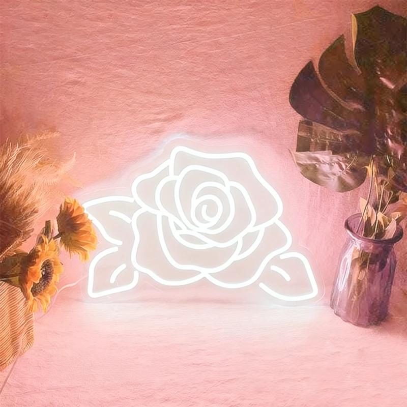 Neon rose light on a pink background with decorative plants.