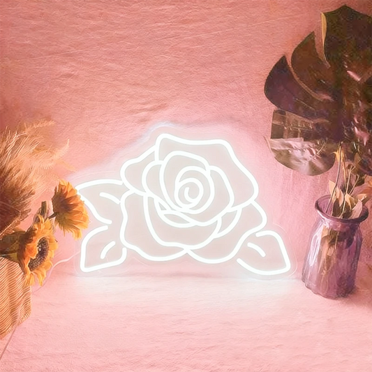 Neon rose light on a pink background with decorative plants.