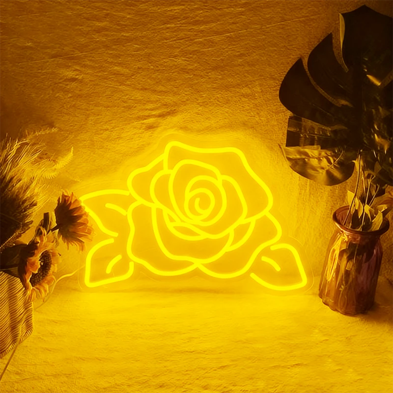 Neon yellow rose shape light on a textured wall with decorative plants.