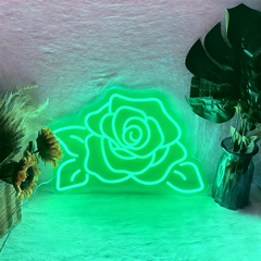 Neon green rose-shaped light on a textured wall with plants around