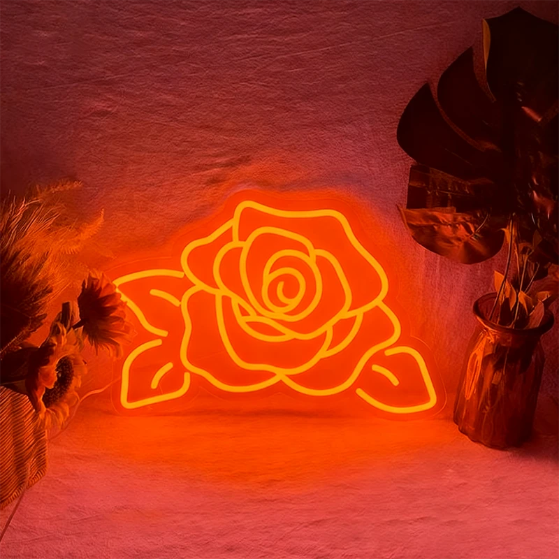 Neon orange rose light fixture on a textured wall with decorative plants.