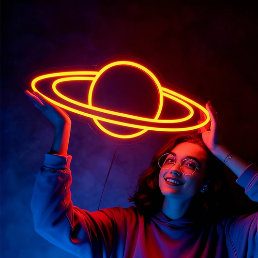 Person holding a neon Saturn light against a dark background