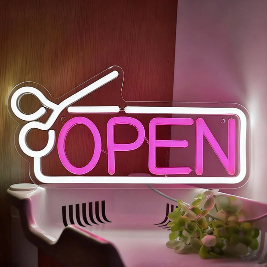 Neon sign with white scissors and hot pink 'OPEN' text on a wooden background