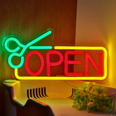 Neon sign with green scissors and red 'OPEN' text on a wooden background