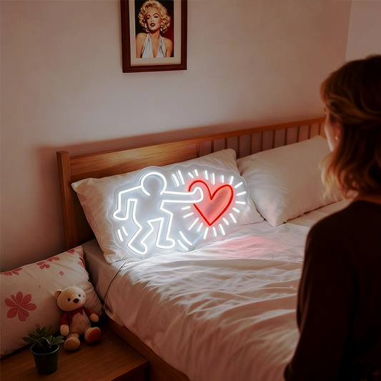 Neon sign of a person with a heart on a bed in a bedroom.