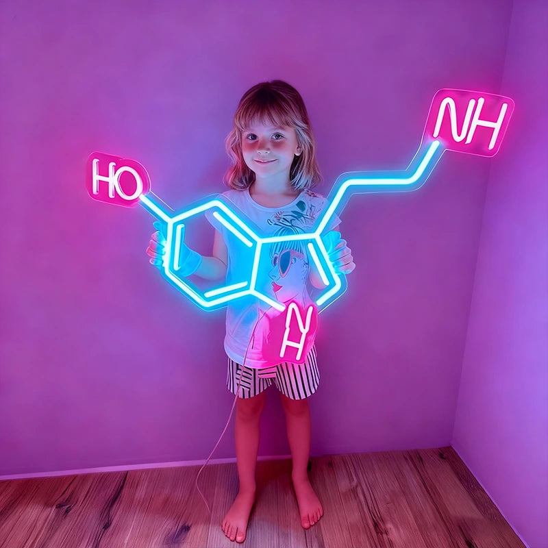 Child holding a neon molecule model against a pink wall