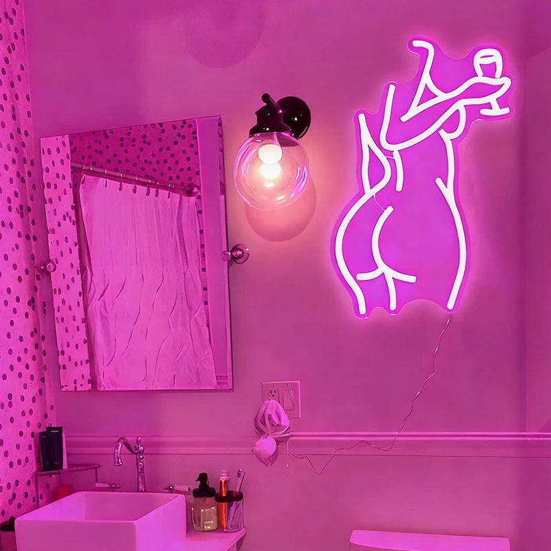 Neon hot pink light of a lady's back on a wall in a bathroom.