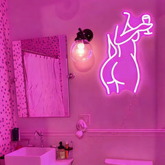 Neon hot pink light of a lady's back on a wall in a bathroom.