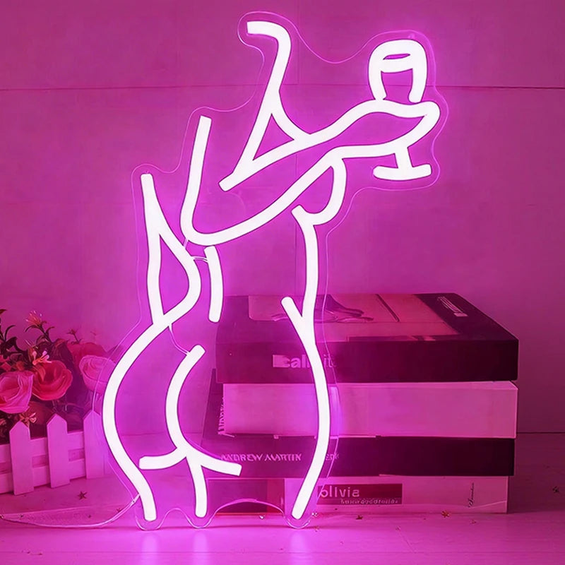 Neon hot pink light shaped like a lady's back in a crouching position on a drak background