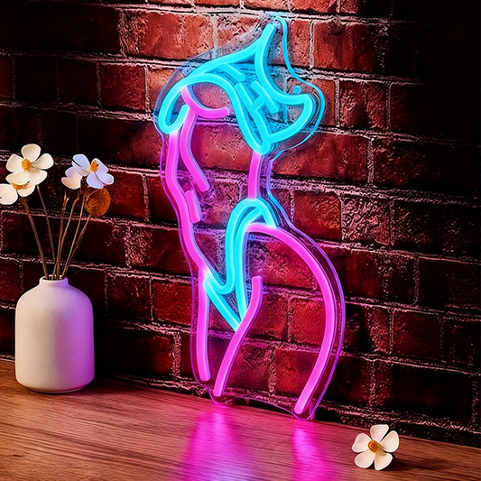 Neon sign shaped like a Woman Body on a brick wall with a vase and flowers on a wooden surface.
