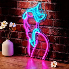 Neon sign shaped like a Woman Body on a brick wall with a vase and flowers on a wooden surface.
