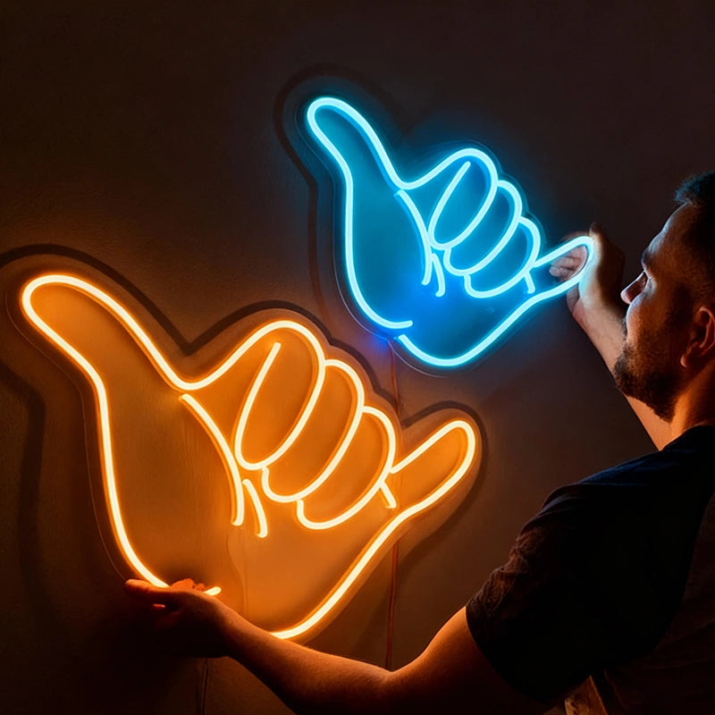 Two neon signs shaped like hands, one orange and one blue, on a dark background.