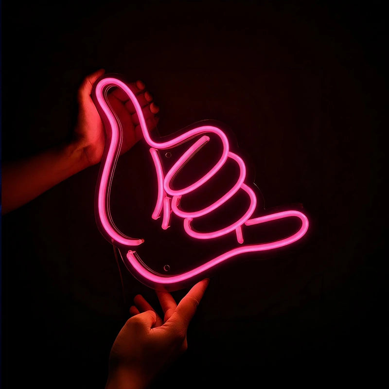 Neon pink hand sign with a thumb up held against a dark background