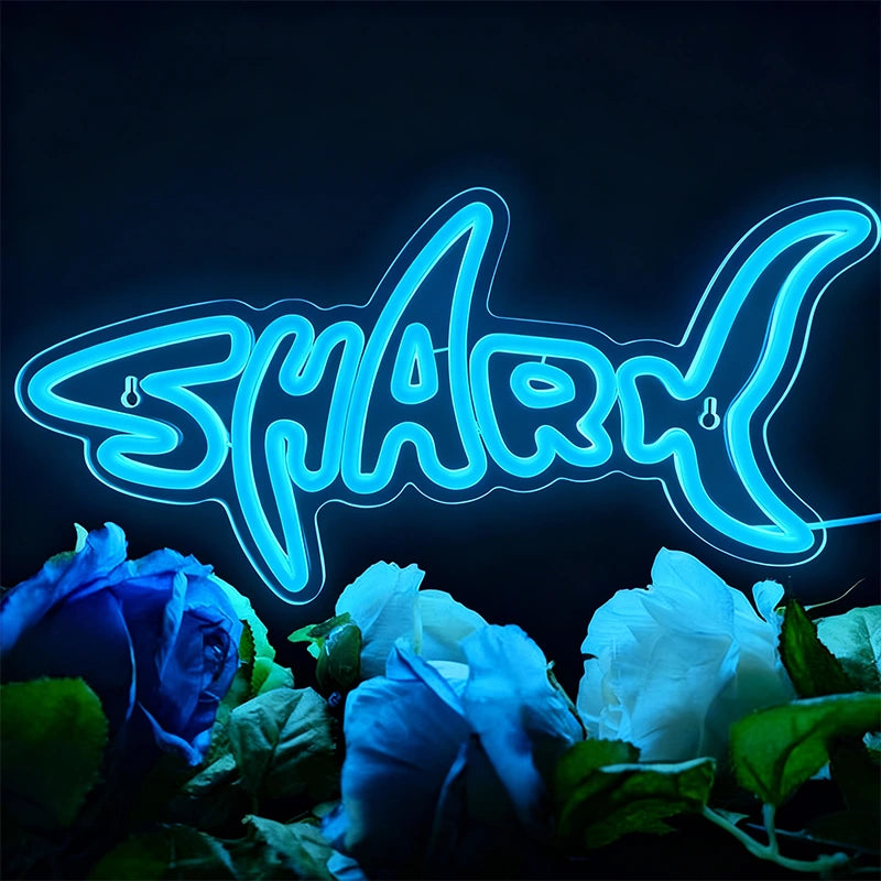 Neon sign with the word 'Shark' surrounded by blue and white roses on a dark background