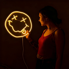 Person holding a smiley face neon light sign with a on a dark background