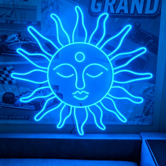 Neon blue sun-shaped sign with face design on a blurred background