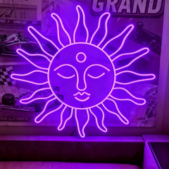 Neon purple sun-shaped light fixture with face design in a room with posters and decor.