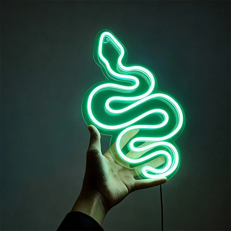 Green neon sign shaped like a snake held by a hand against a dark background