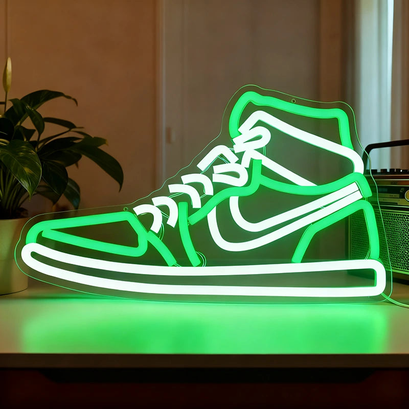 Neon light shaped like a sneaker on a table with a plant and box in the background