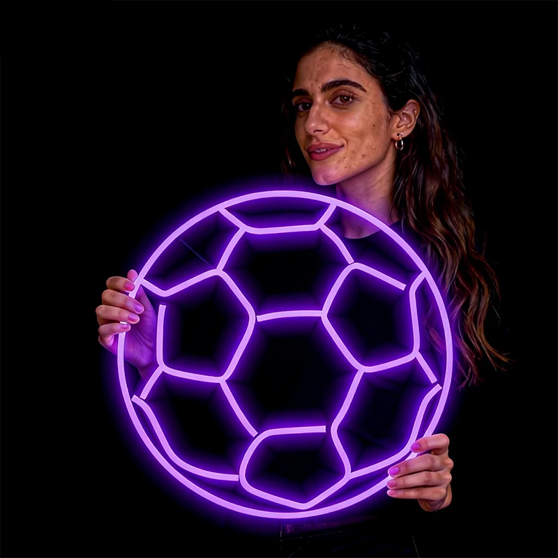 Woman holding a neon purple soccer ball against a black background