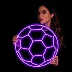 Woman holding a neon purple soccer ball against a black background