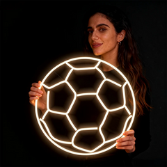 Woman holding a neon soccer ball against a black background