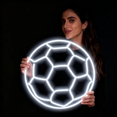 Woman holding a neon soccer ball against a black background