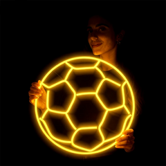 Person holding a glowing neon soccer ball against a dark background