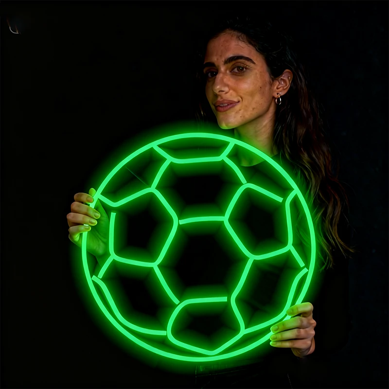 Woman holding a neon green soccer ball against a black background
