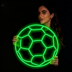 Woman holding a neon green soccer ball against a black background