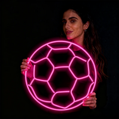 Woman holding a pink neon soccer ball against a black background