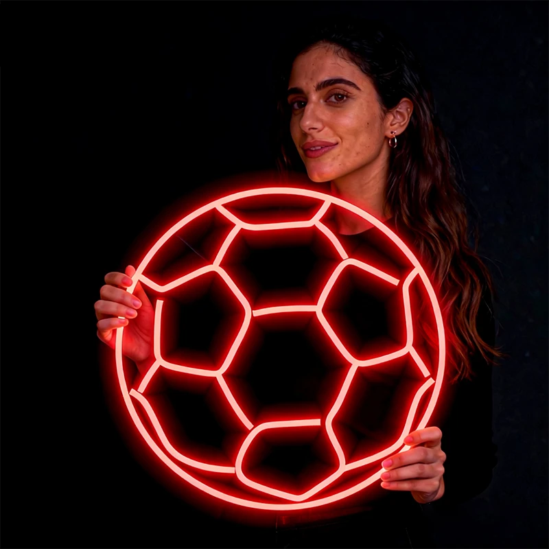 Woman holding a glowing red soccer ball against a black background