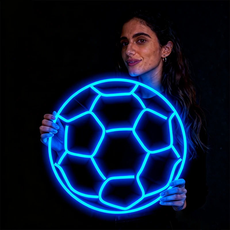 Woman holding a glowing ice blue soccer ball against a black background