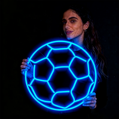 Woman holding a glowing ice blue soccer ball against a black background