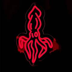Person holding a red squid neon sign in the dark.